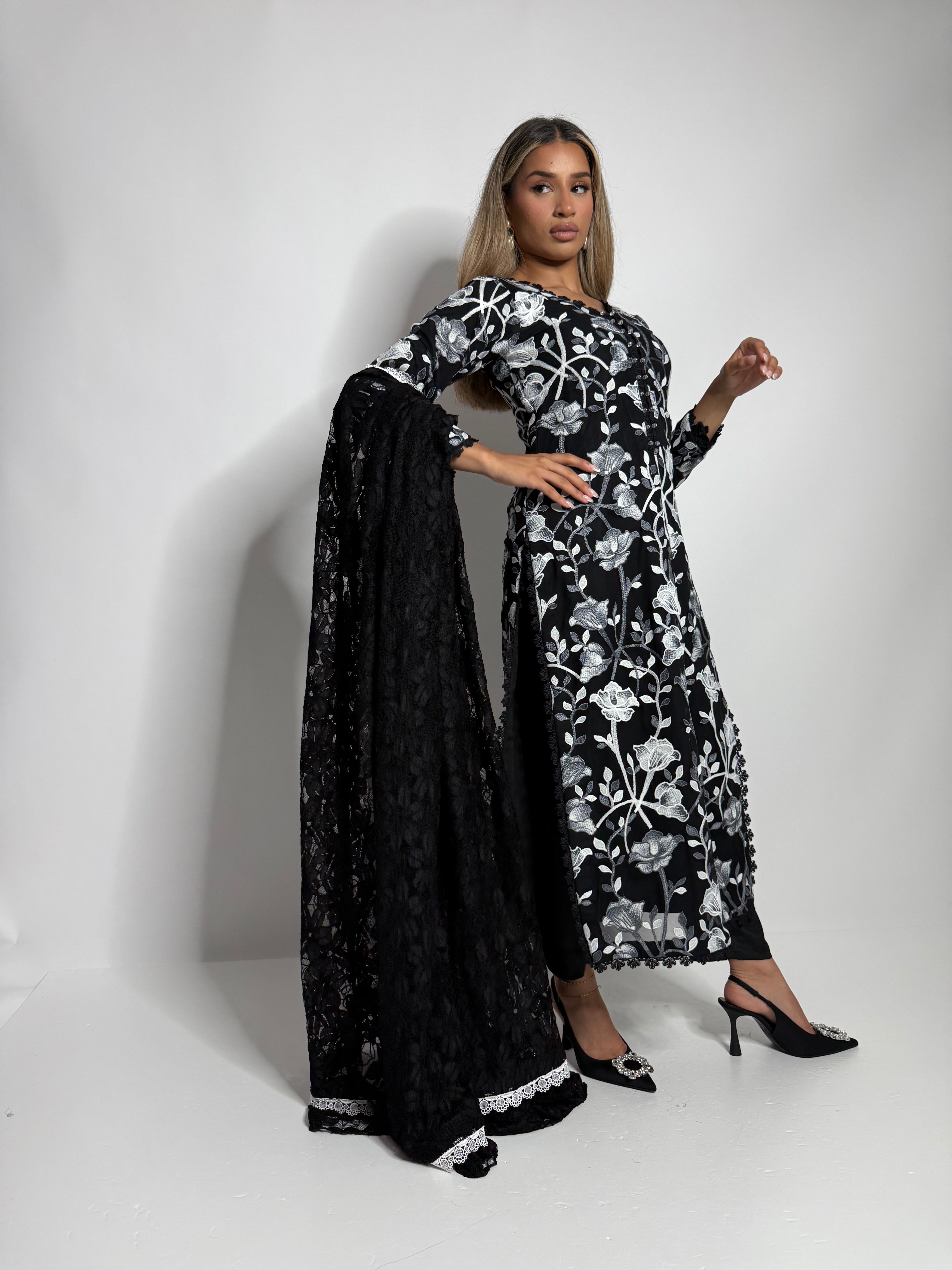 Close up of lace dupatta paired with black floral net kameez for refined evening wear.